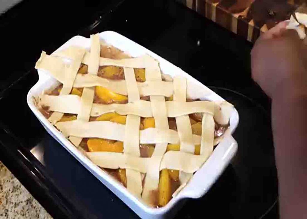 Adding the strip crust on top of the peach cobbler