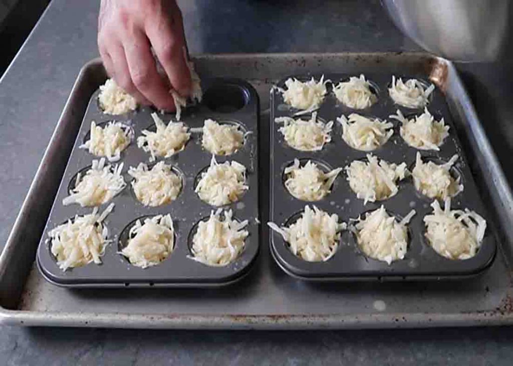 Transferring the potato poppers onto the muffin tray