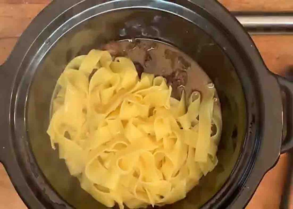Adding the egg noodle pasta to the crockpot