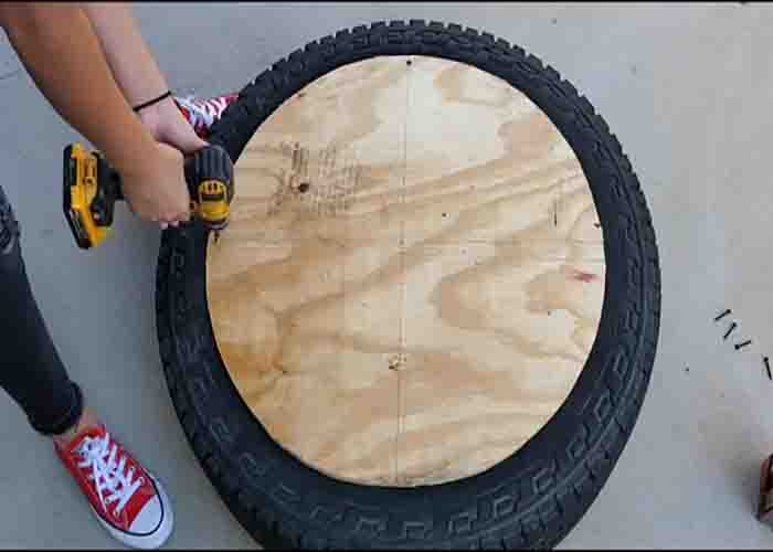 Screwing the wood to the tire to make a table