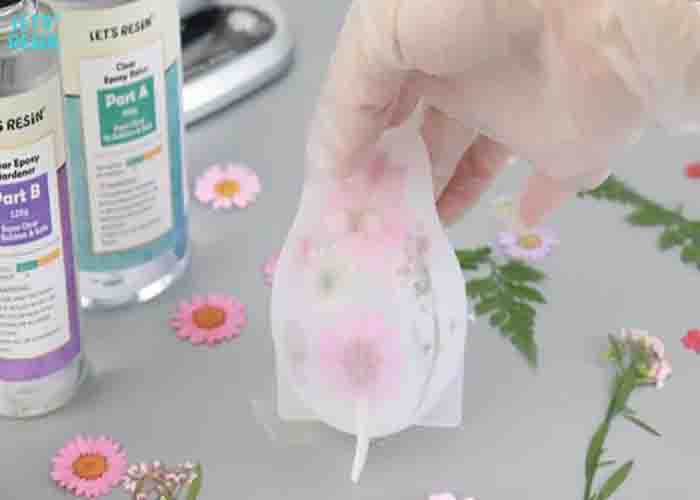 Gluing the dried flowers inside the light bulb silicone mold
