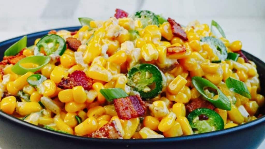 Steakhouse Creamed Corn in a bowl with bacon, green onions, and serrano peppers on top