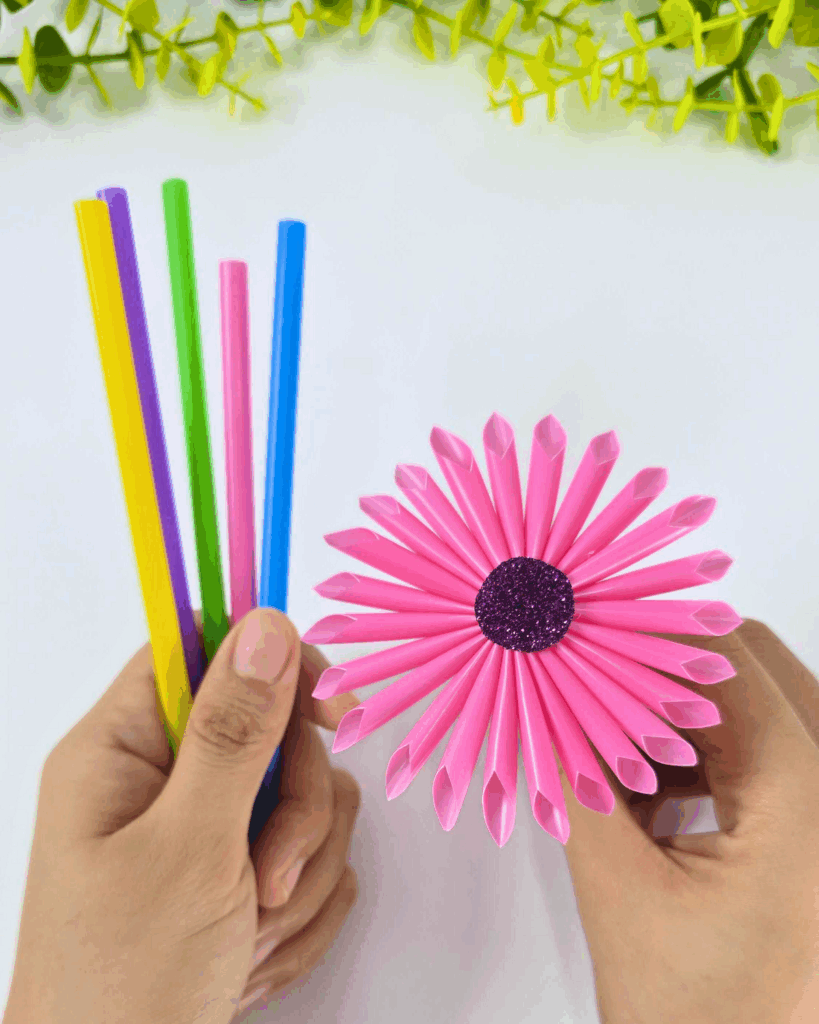 Holding a straw and a finished flower to demonstrate steps in this easy and cute DIY craft.