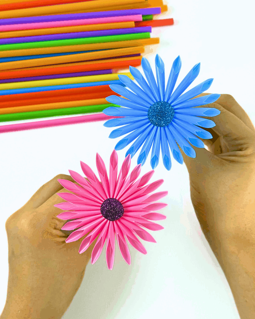 Holding two colorful cocktail straw flowers with other straws in the background for a cute display.
