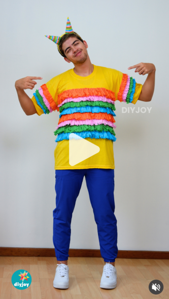 Best DIY Costumes - vertical video thumbnail of the young man in the finished piñata costume pointing both index fingers at his fringed shirt, with a translucent play button in the centre and a DIY JOY logo in the corner