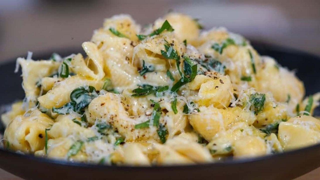 Creamy garlic pasta in a skillet with baby spinach and a shower of freshly grated parmesan stirred through