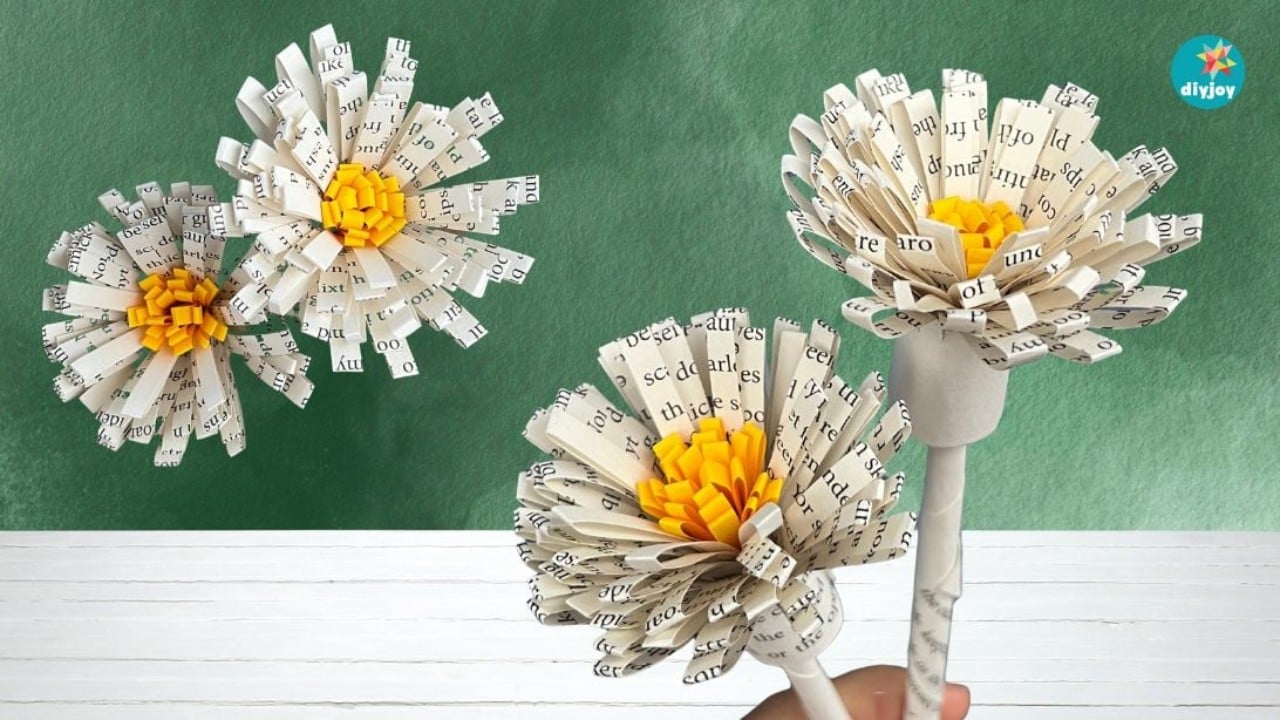 DIY book page paper flowers, three fringed blooms cut from printed book pages with yellow centers, one held up