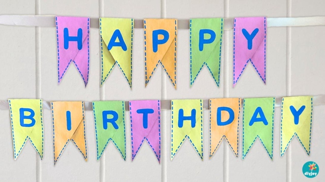 DIY birthday banner with toilet paper rolls, pastel painted cardboard pennants spelling HAPPY BIRTHDAY in blue letters