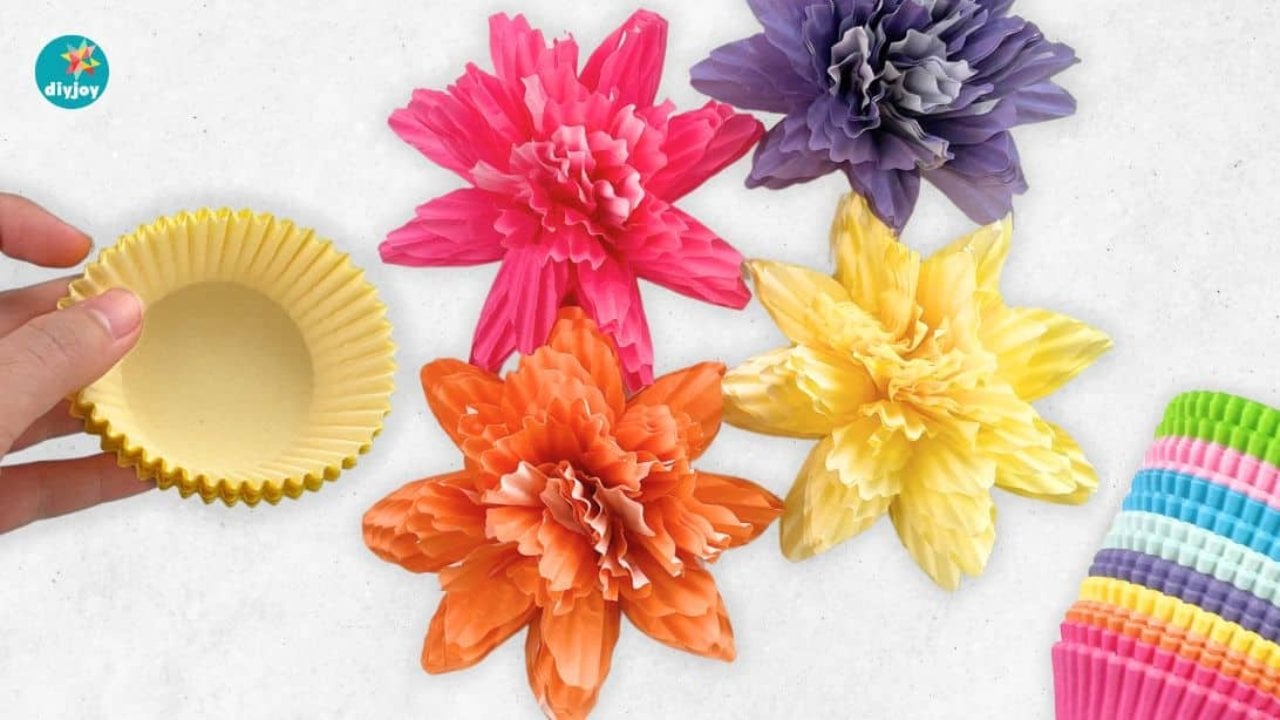 Paper flowers with cupcake liners, pink, orange, purple and yellow liner flowers beside a stack of colorful baking cups