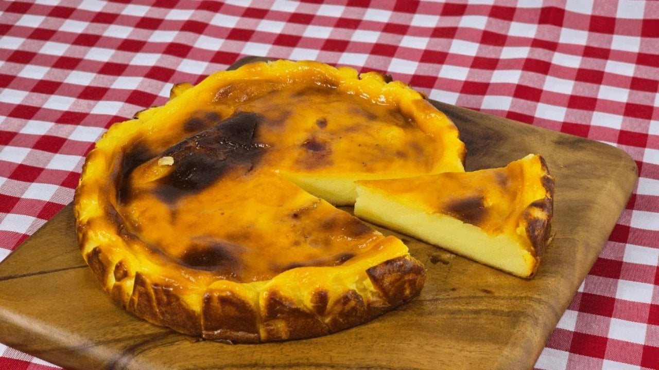 Rustic baked yogurt cheesecake with a dark browned top on a wooden board with one slice cut and lifted