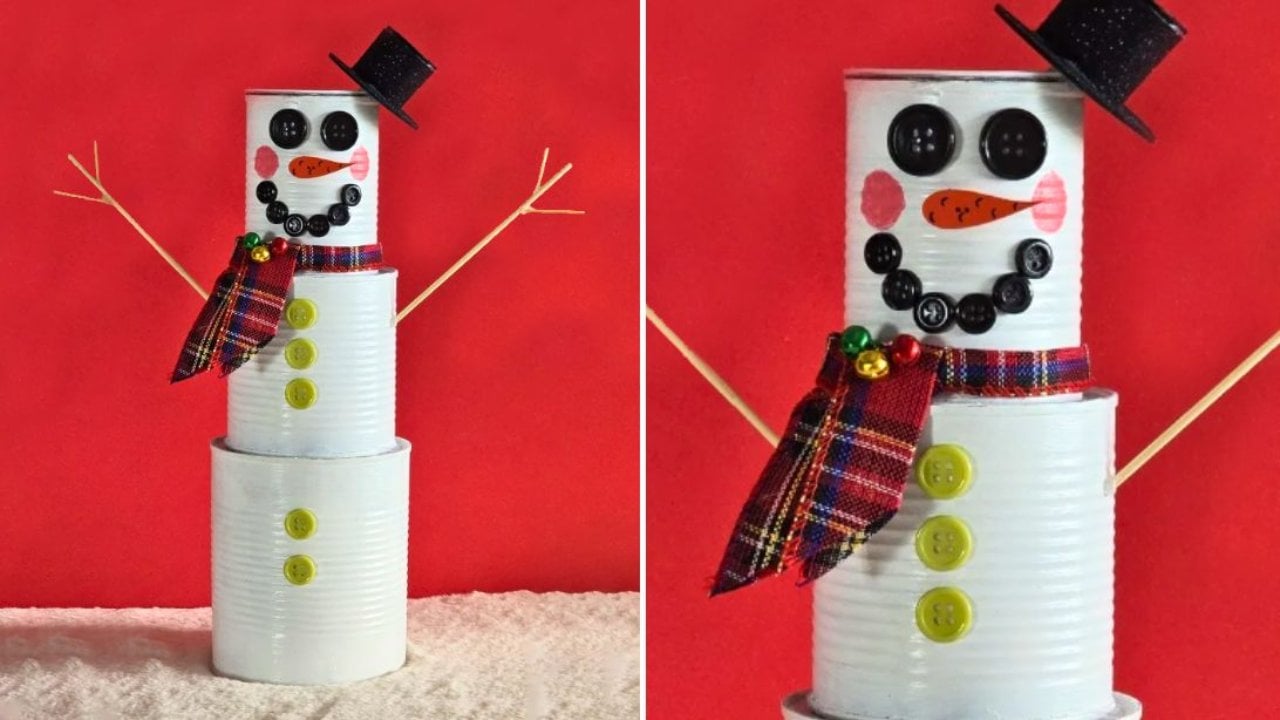 Three stacked tin cans painted white as a snowman with black button eyes, carrot nose and red plaid ribbon scarf