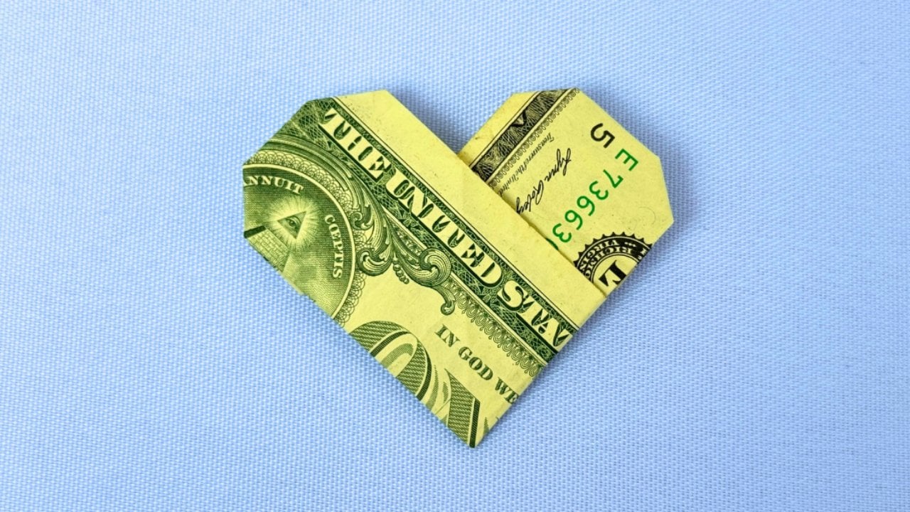 A dollar bill folded into an origami heart shape, an easy money gift idea for Valentine's Day for him