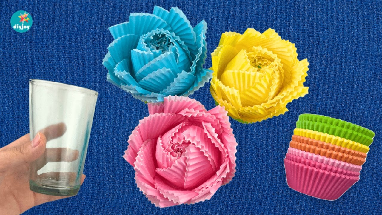 Easy Paper Flowers Made With Cupcake Liners Three ruffled paper flowers in turquoise, yellow and pink made from cupcake liners, with a glass and a stack of liners