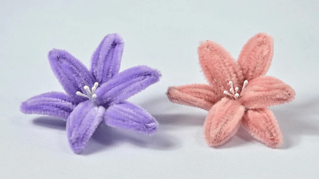 Handmade pipe cleaner lily flowers in soft pastel colors arranged in a vase, an easy DIY chenille stem craft.
