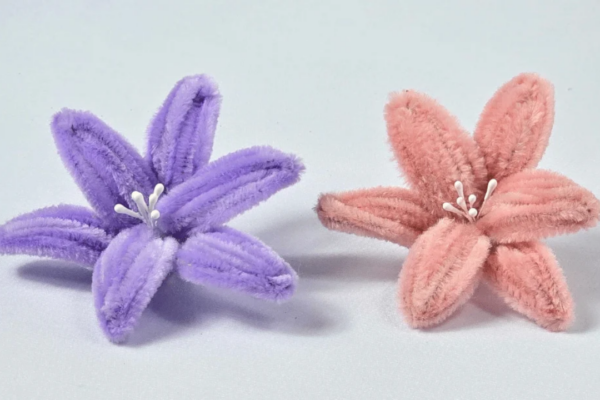 Handmade pipe cleaner lily flowers in soft pastel colors arranged in a vase, an easy DIY chenille stem craft.