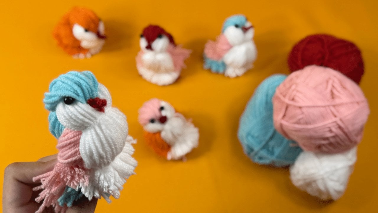 Easy DIY Yarn Birds | 5 Minute Spring Craft Easy DIY yarn birds in orange, white, blue and pink yarn with bead eyes and fringe tails beside balls of yarn on orange