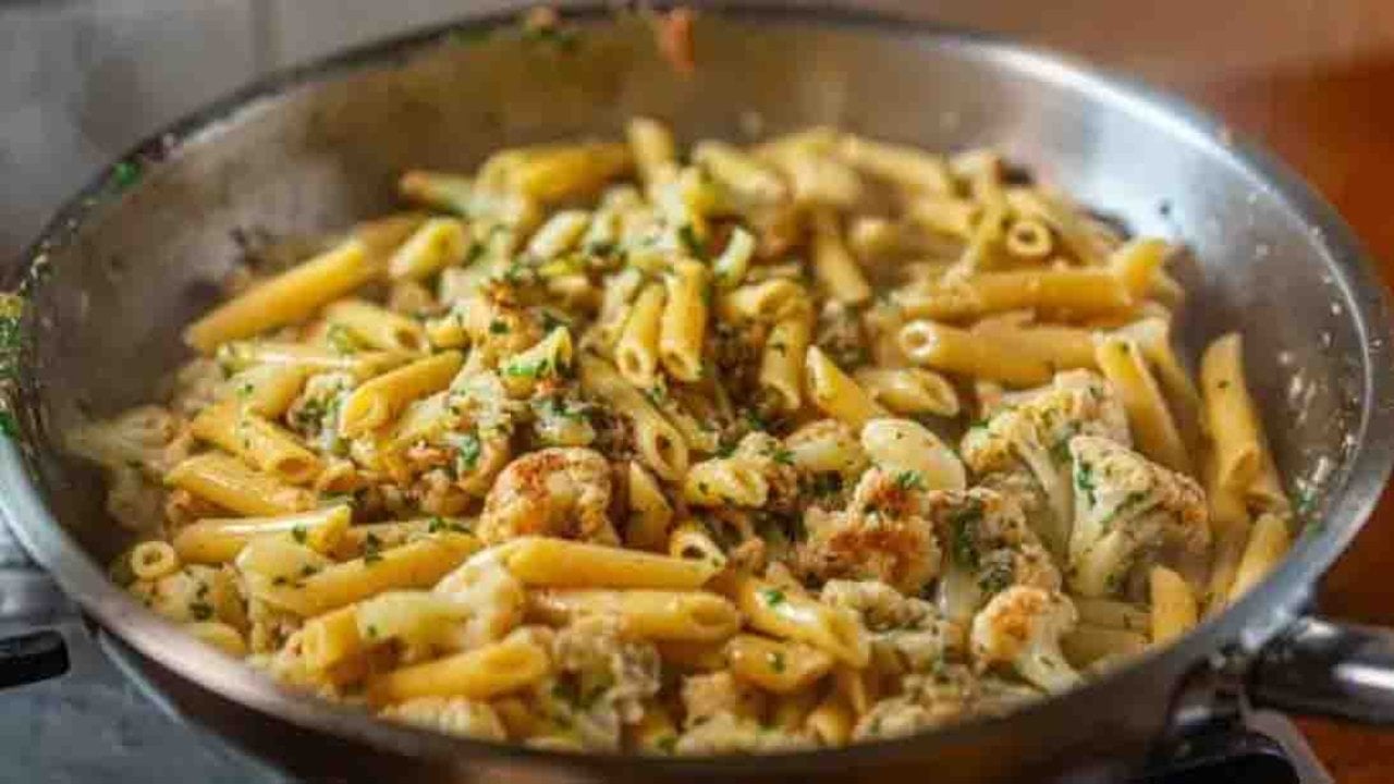 Cauliflower and garlic penne pasta with capers, lemon zest, parsley and grated pecorino romano ready to serve at home