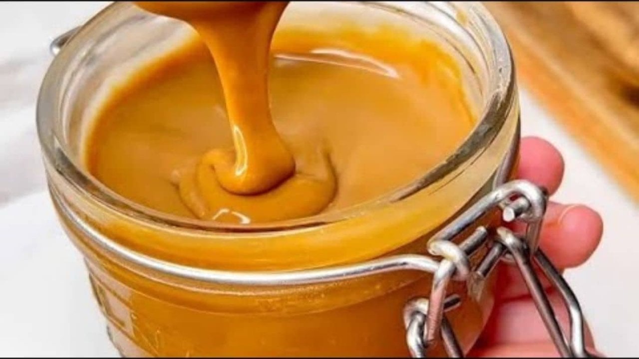Homemade Coffee Jam, No Fruit Recipe Coffee jam in a small glass jar, thick and caramel colored, spread on a slice of toasted bread with butter