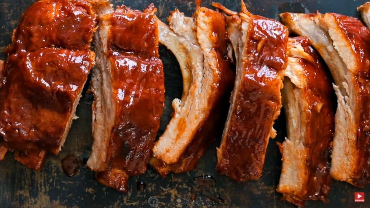 Rack of glazed instant pot barbecue ribs sliced into portions with a dark sticky sauce on the cut edges