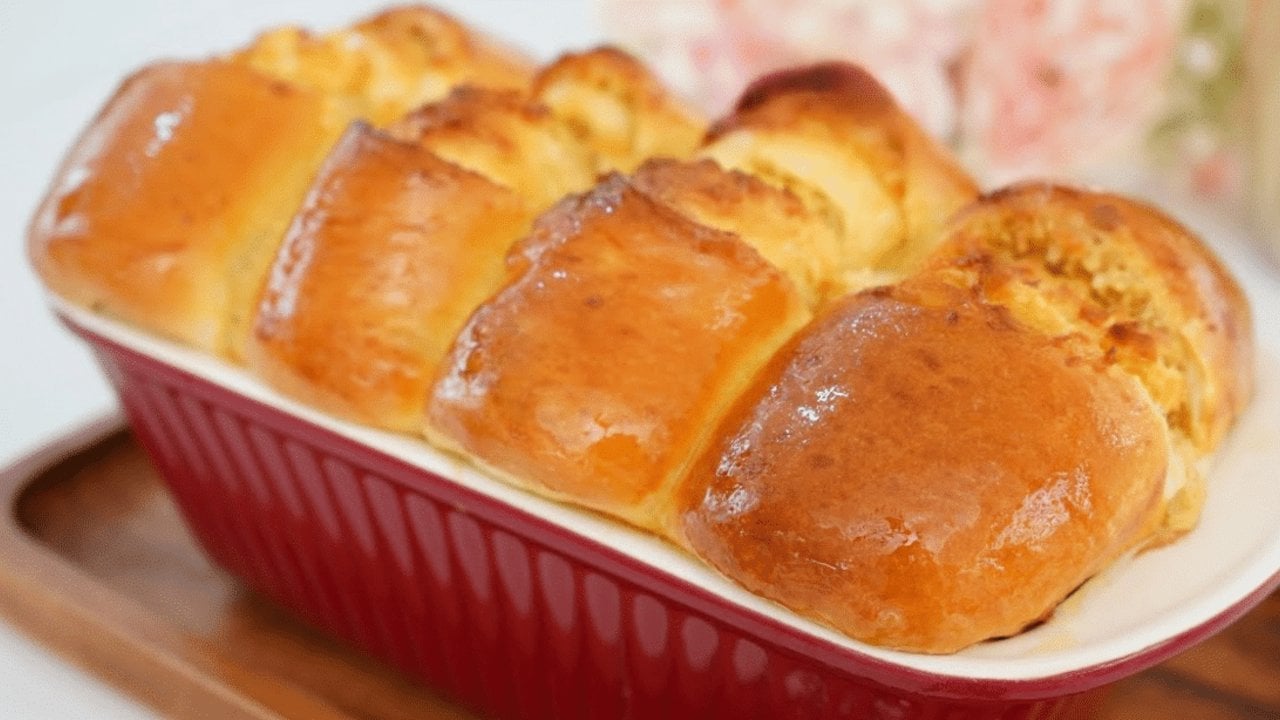 Easy Coconut Dream Loaf Bread Recipe Coconut dream loaf baked whole as five glossy golden pull-apart rolls in a deep red fluted ceramic dish
