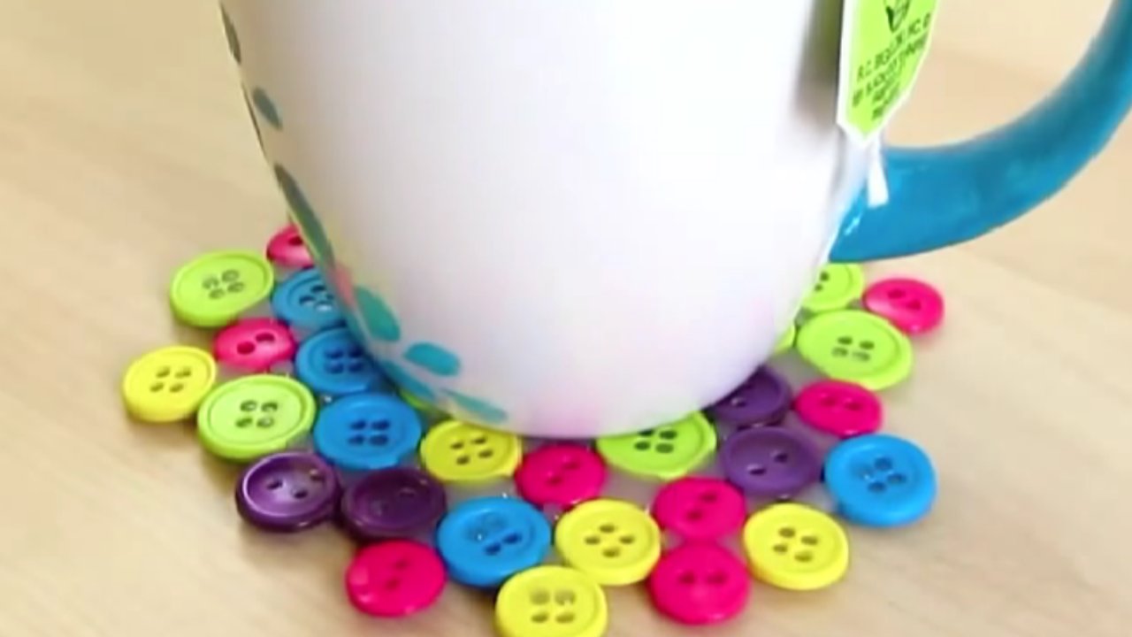 Easy DIY button coaster, a bright green, pink, blue and yellow button coaster under a white mug on a wooden table