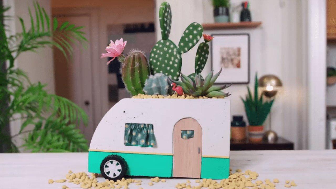 Concrete vintage camper planter, a small white and teal cast cement camper trailer planted with cactus and succulents