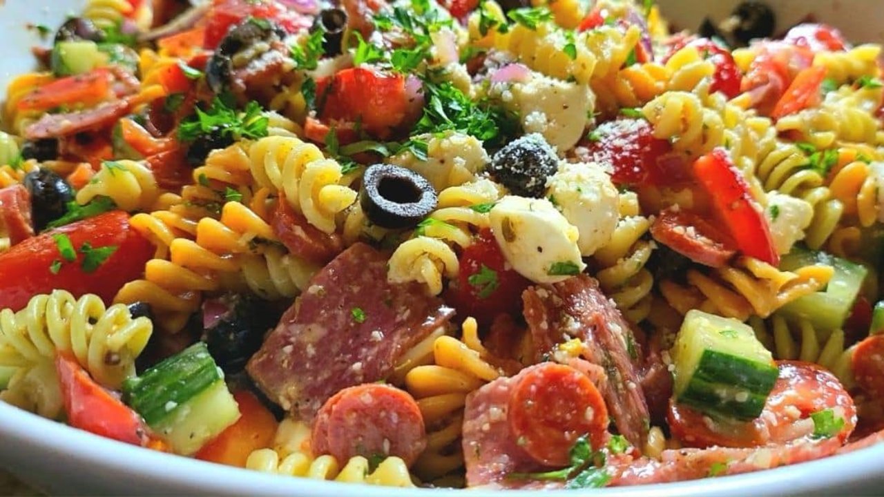 Italian pasta salad with rotini, pepperoni, salami, mozzarella pearls, cucumber, tomatoes and black olives