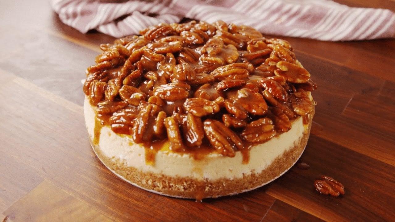 Easy pecan pie cheesecake with whole pecans in a caramel topping over a brown sugar cheesecake layer