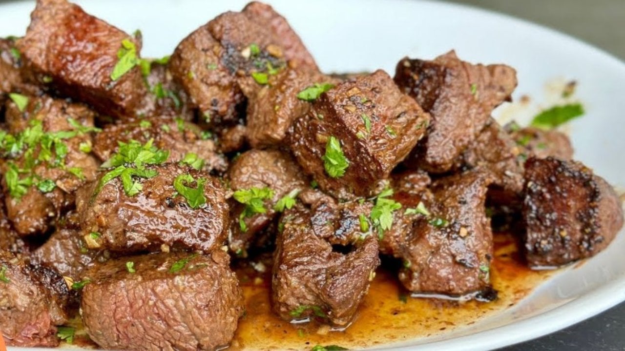 Garlic butter steak bites for two, cubed fillet steak seared in a hot pan and glossy with garlic butter sauce