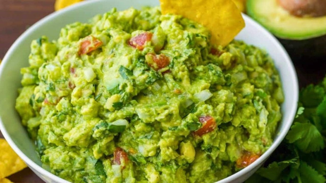 Best Ever Guacamole Recipe, Three Ways Best ever guacamole, a white bowl of chunky green guacamole with tortilla chips and half an avocado alongside