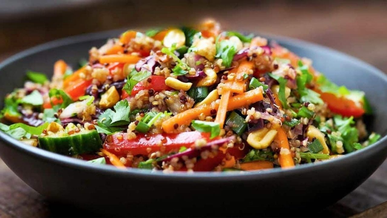 Healthy protein quinoa bowl layered with red bell pepper, shredded purple cabbage and vegetables over quinoa
