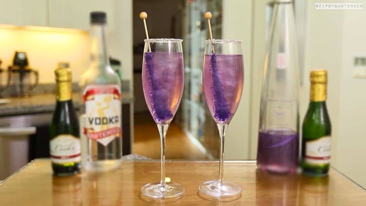 Purple Shimmering Champagne Cocktail Two silver sugar rimmed flutes of pale lavender shimmering champagne, each with a purple rock candy stick