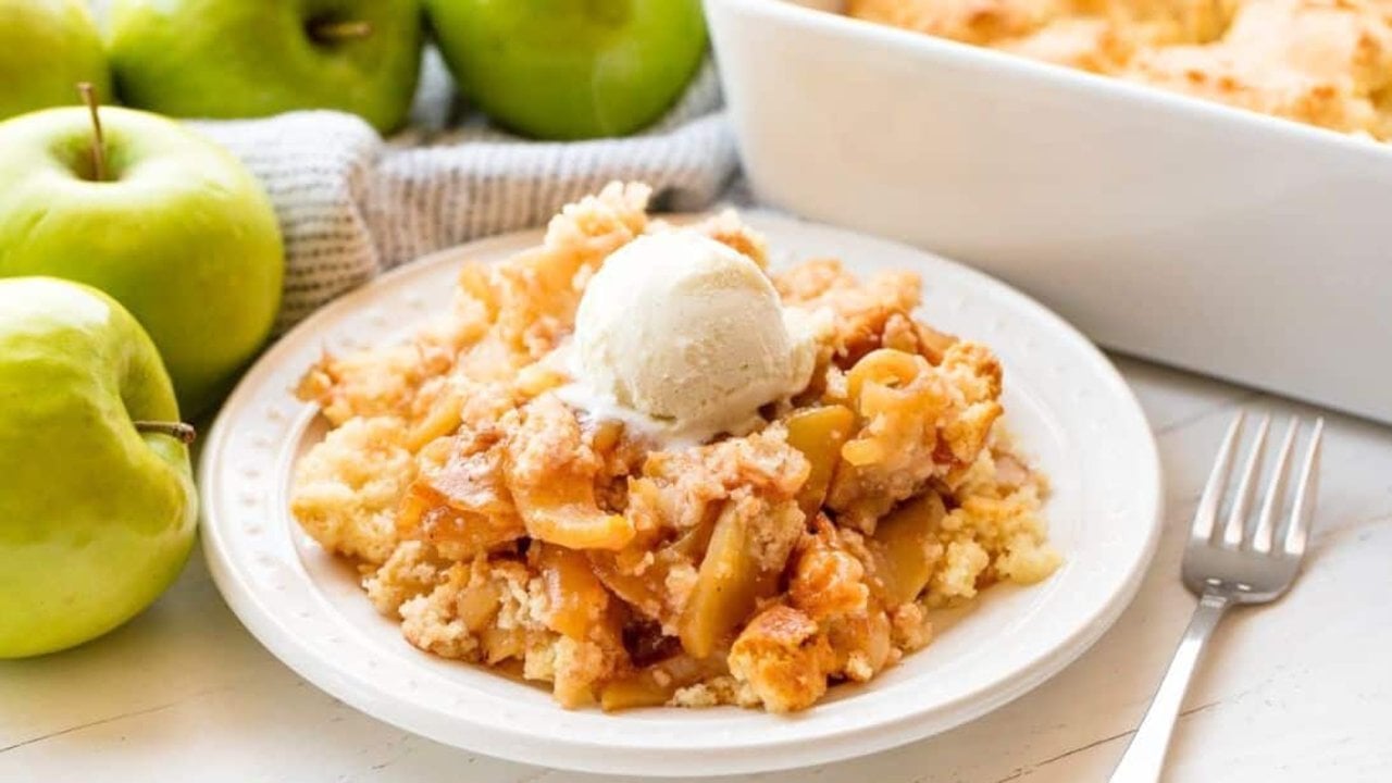 Old fashioned apple cobbler in a baking dish with cinnamon apples under a golden biscuit style topping