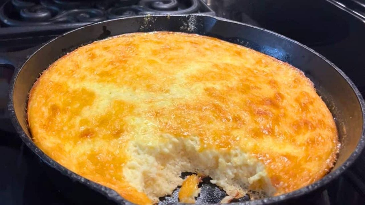 Southern style spoon bread baked in a cast iron skillet with a soft golden top and a creamy pudding texture