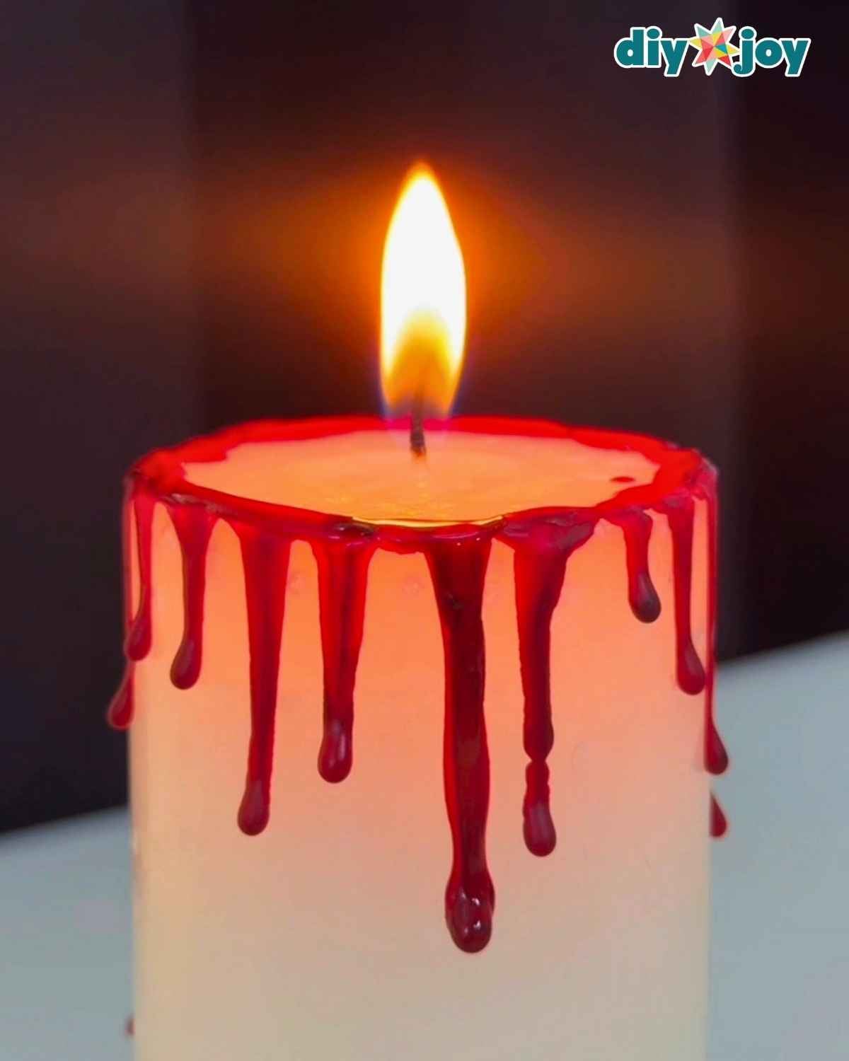 Step 3, a finished bloody candle with hardened red crayon blood drips ready for Halloween