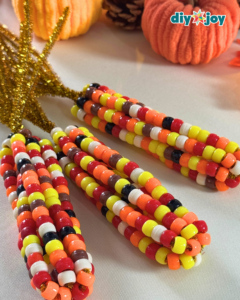 Thanksgiving Crafts - beaded Indian corn displayed with mini pumpkins