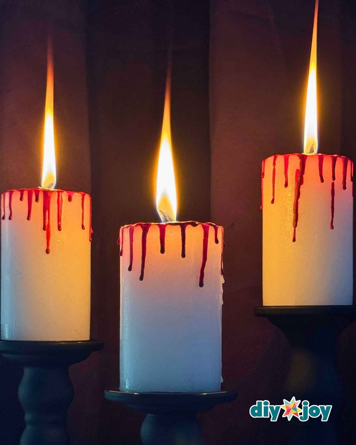 Spooky bloody candles grouped together as easy Halloween decor with dripping red crayon wax