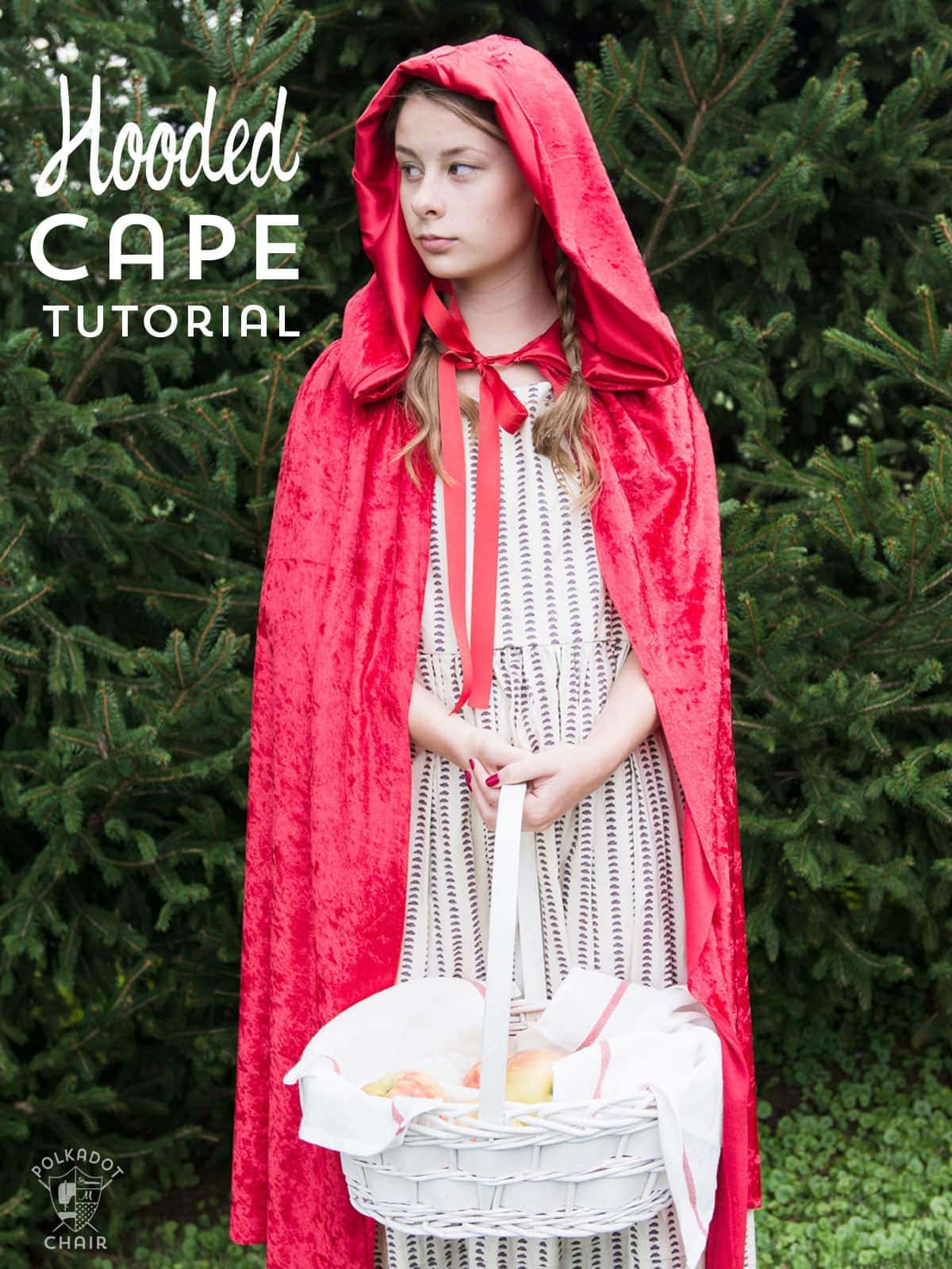 Girl in a red lace hooded cape over a striped dress, holding a white basket in front of a green fir tree