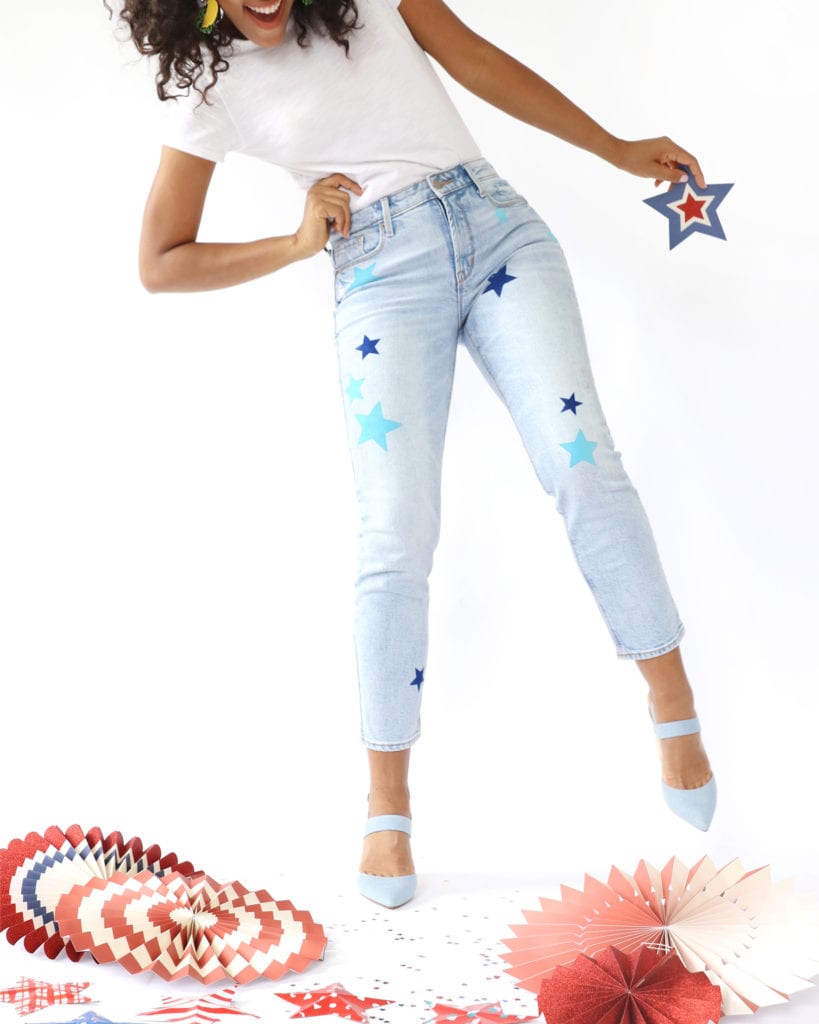 Pale blue jeans stenciled with scattered blue and navy stars, worn with a white tee and pale blue heels
