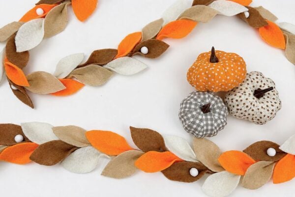 DIY fall leaf garland made from felt draped along a fireplace mantel