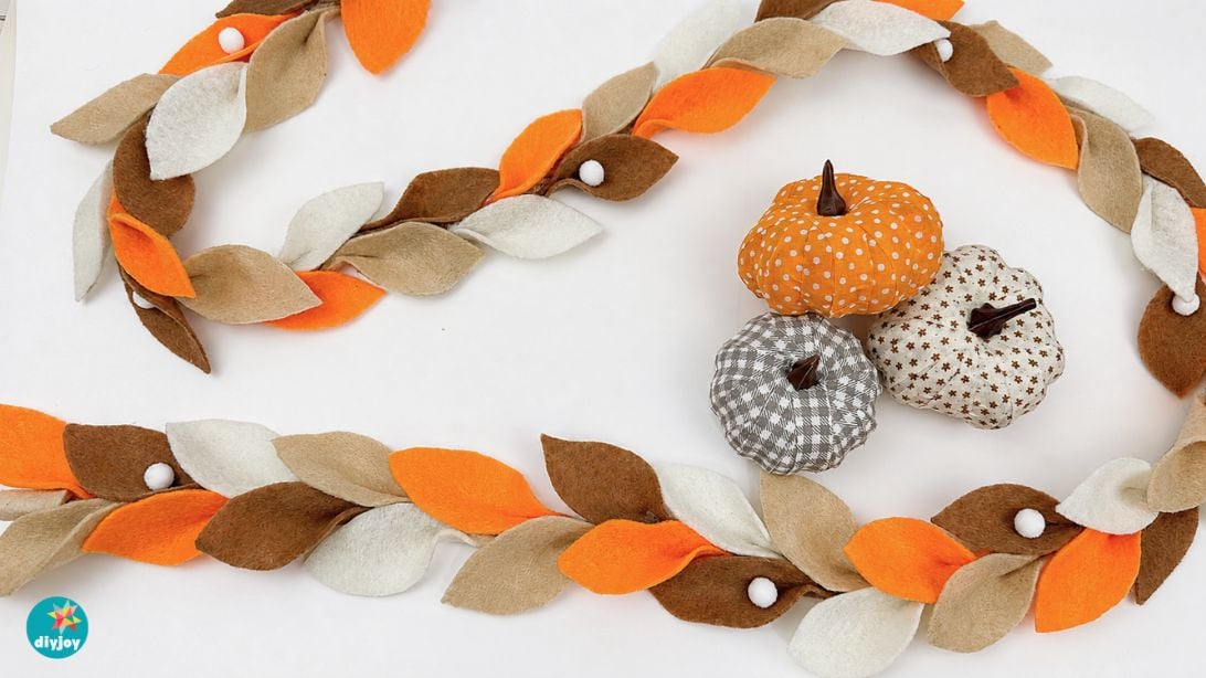 DIY fall leaf garland made from felt draped along a fireplace mantel