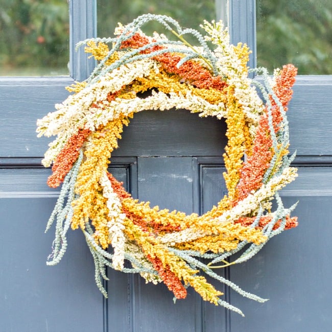 Autumn wreath built up with looped ribbon and clusters of fall flowers, an easy wreath for a front door