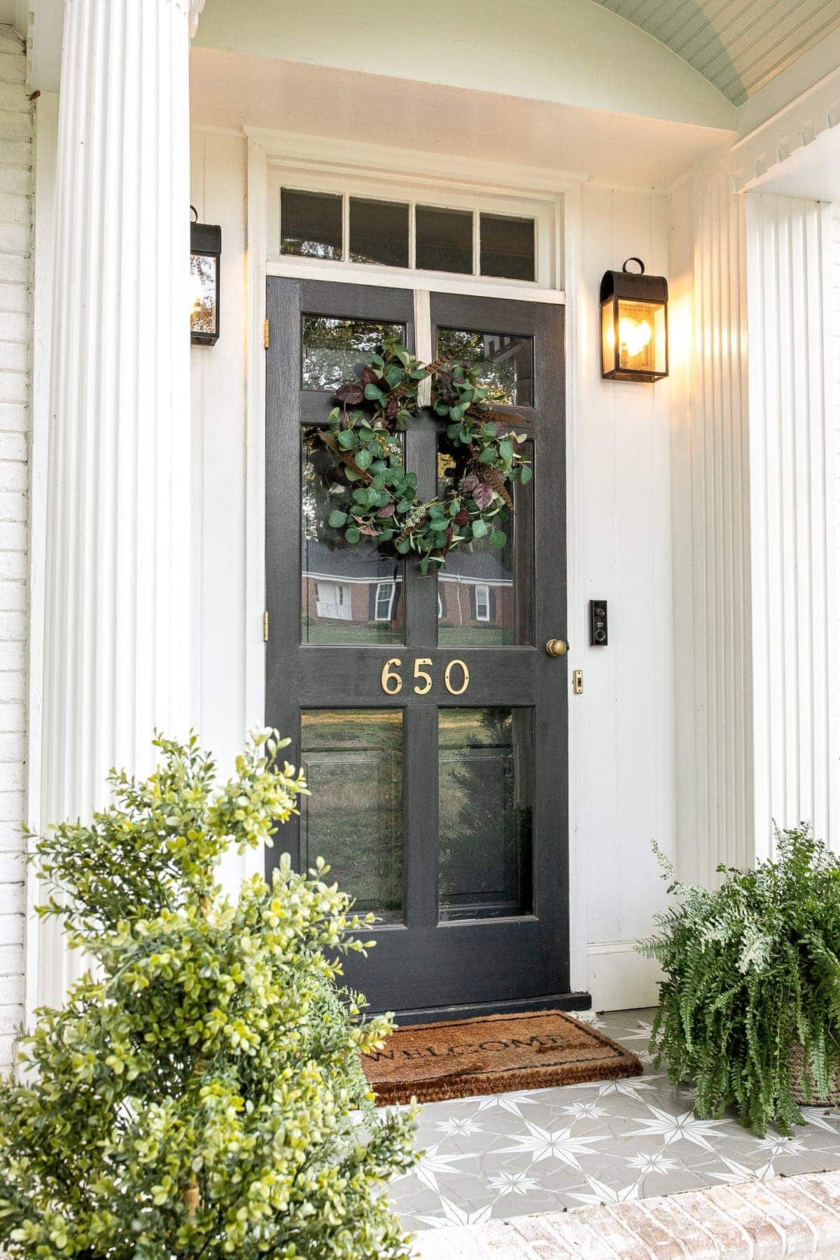 Neutral early autumn wreath of dried eucalyptus and feathers on a pale door, a soft seasonal transition