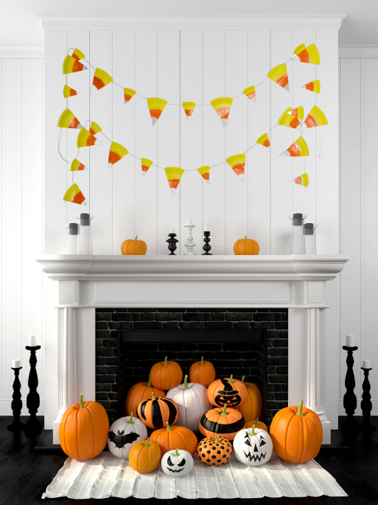 DIY paper plate candy corn banner for fall, orange and yellow painted paper plate triangles strung together over a mantel