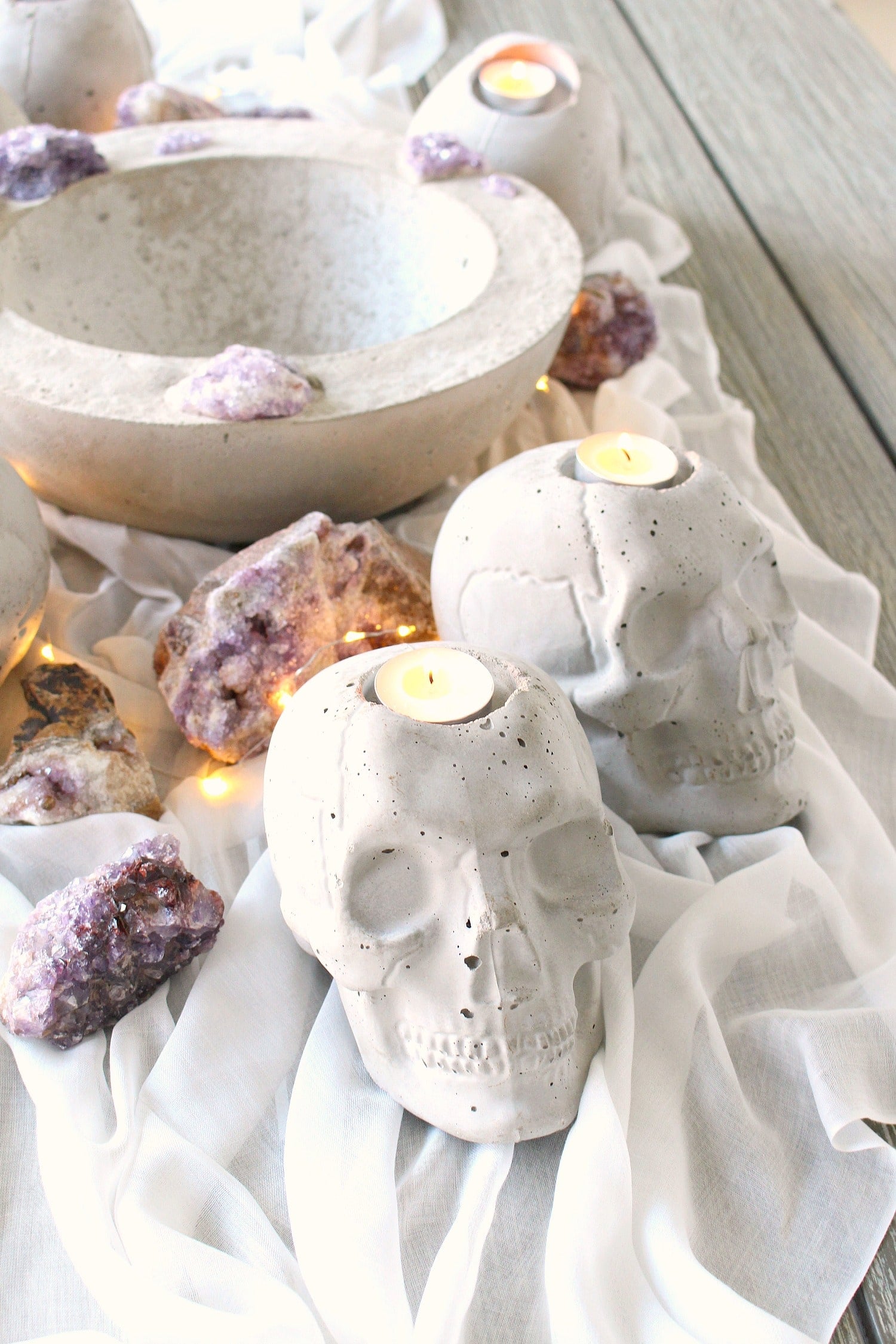 Concrete skull tea light holders glowing with candles on a dark table