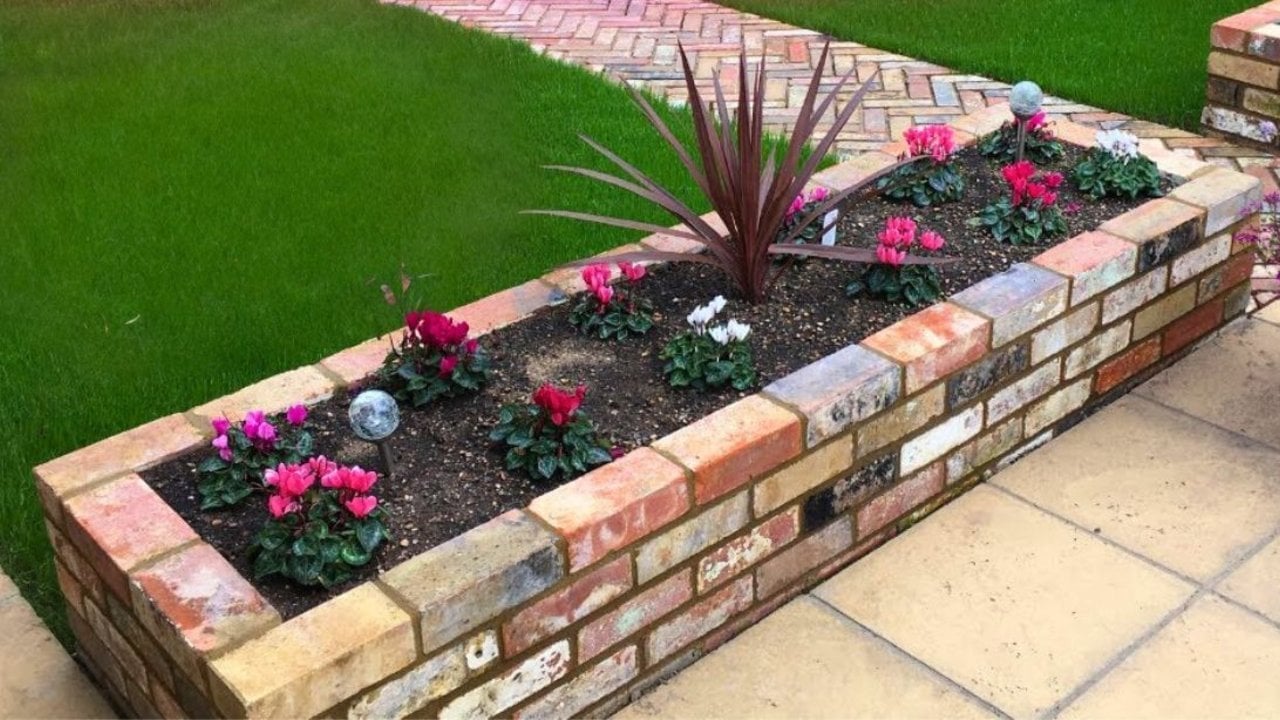 Outdoor fall project, end-of-season yard care and seasonal planting inspiration, showing brick raised yard planter