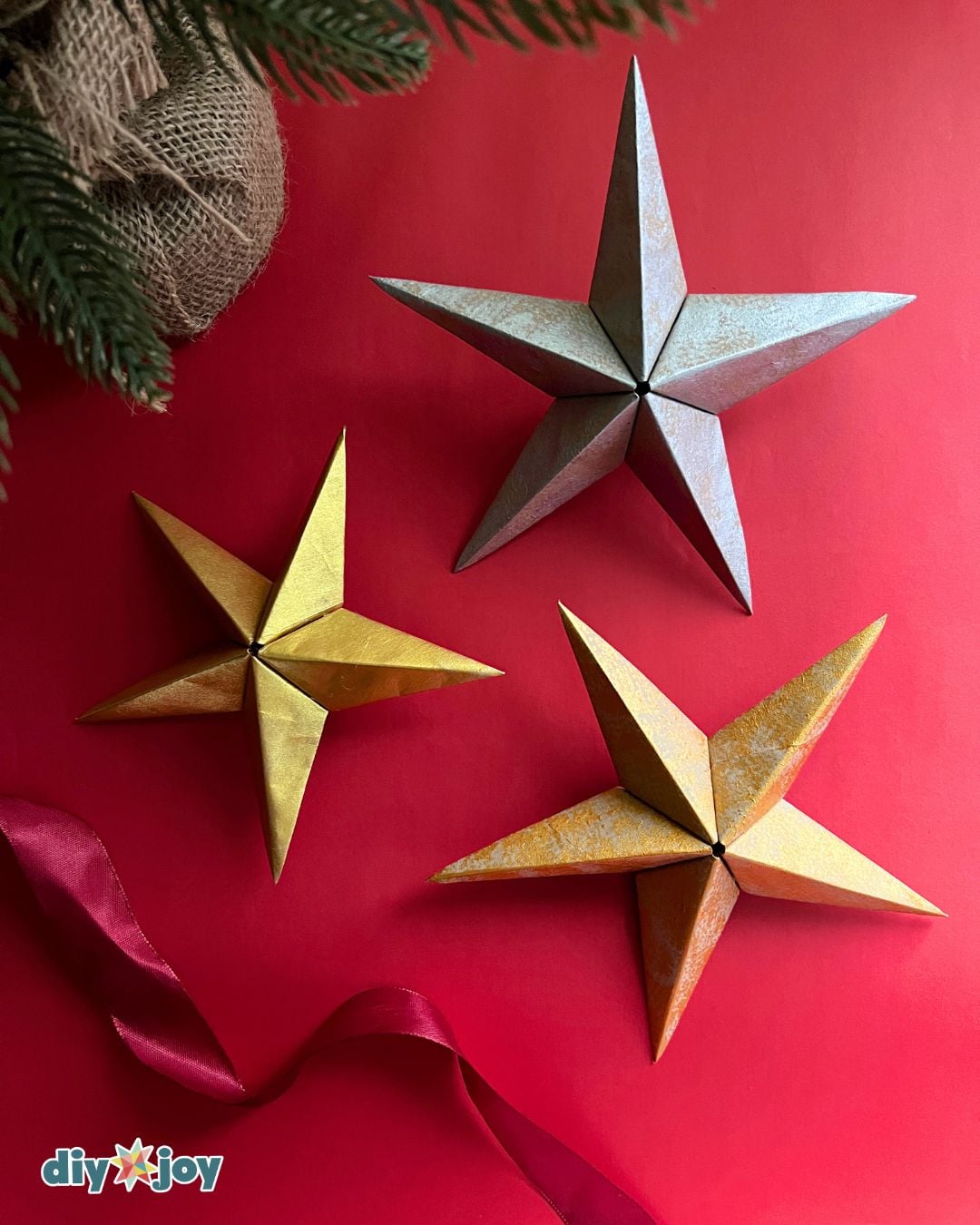 DIY Christmas ornament - silver and gold paper bag star ornaments with red ribbon, ready for the tree
