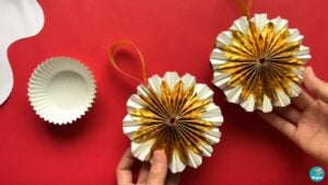 DIY Christmas ornaments made from gold metallic cupcake liners, shown finished with ribbon beside an unfolded liner