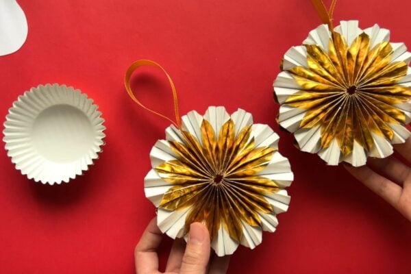 DIY Christmas ornaments made from gold metallic cupcake liners, shown finished with ribbon beside an unfolded liner