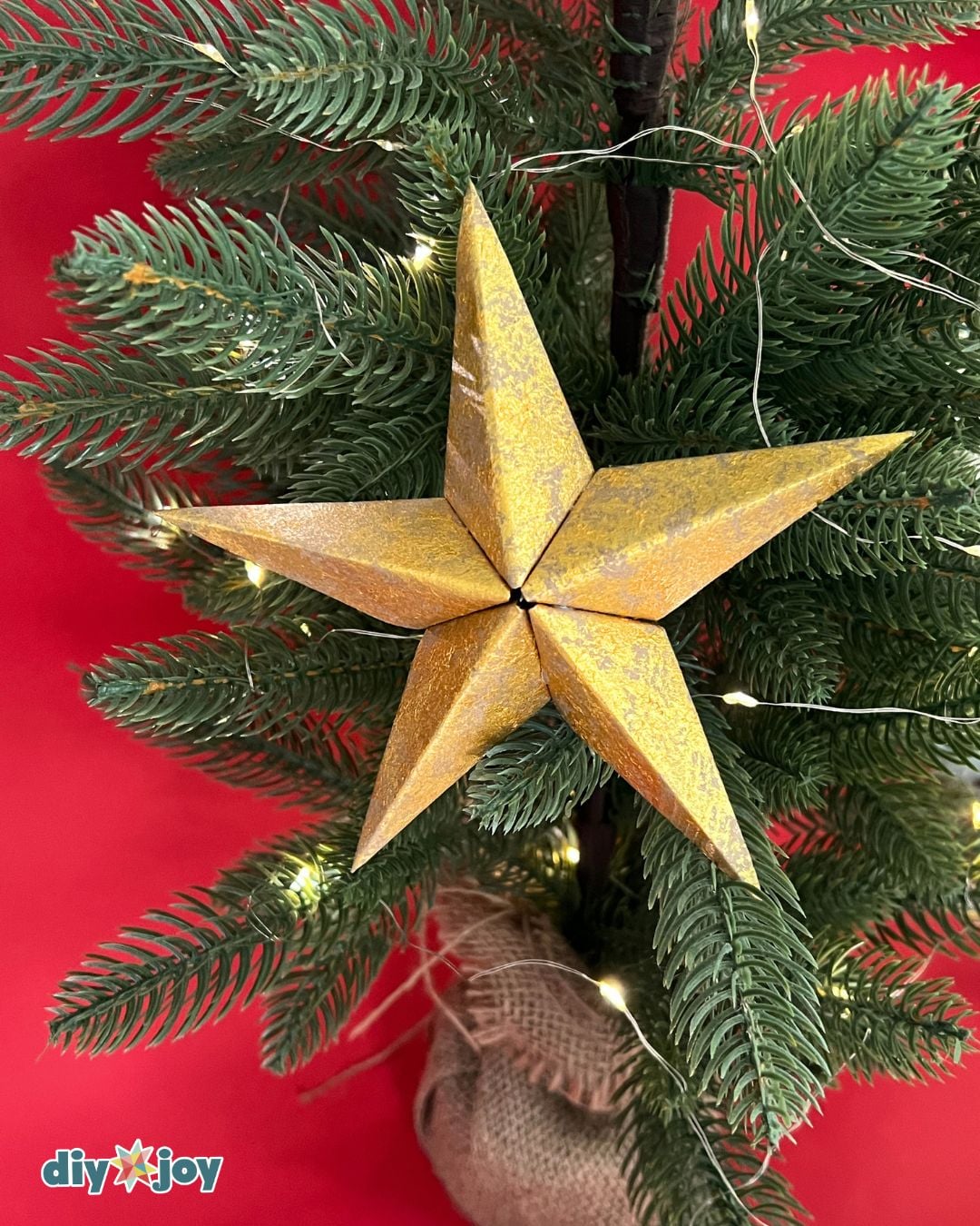 DIY Christmas star ornaments - three silver paper stars styled with pine and ribbon, easy homemade decor